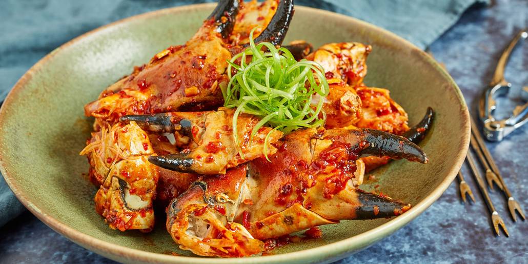 Char-grilled black lava crab topped with scallions on a stone bowl