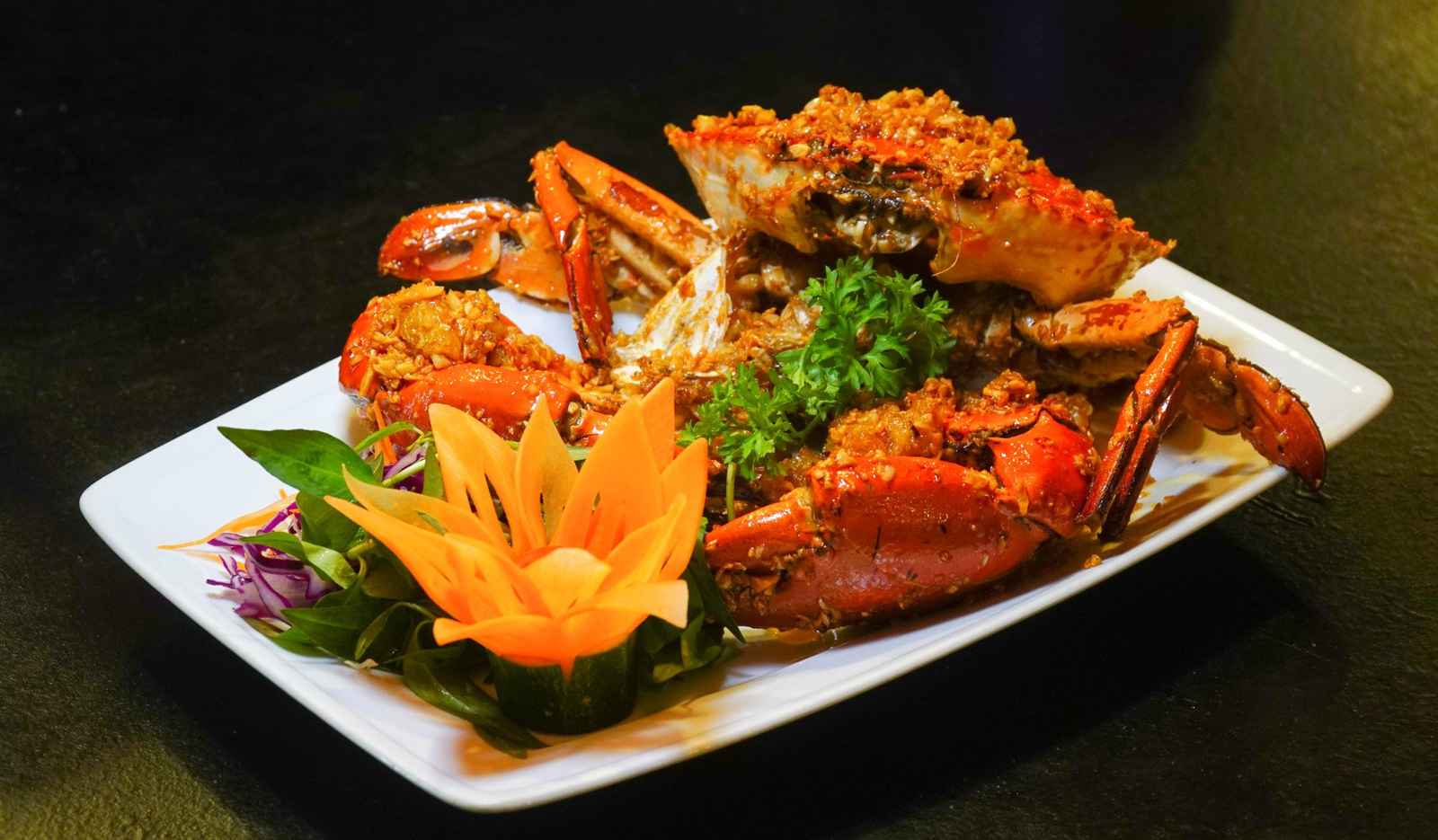 Garlic butter Ca Mau crab plated with a carved carrot flower garnish