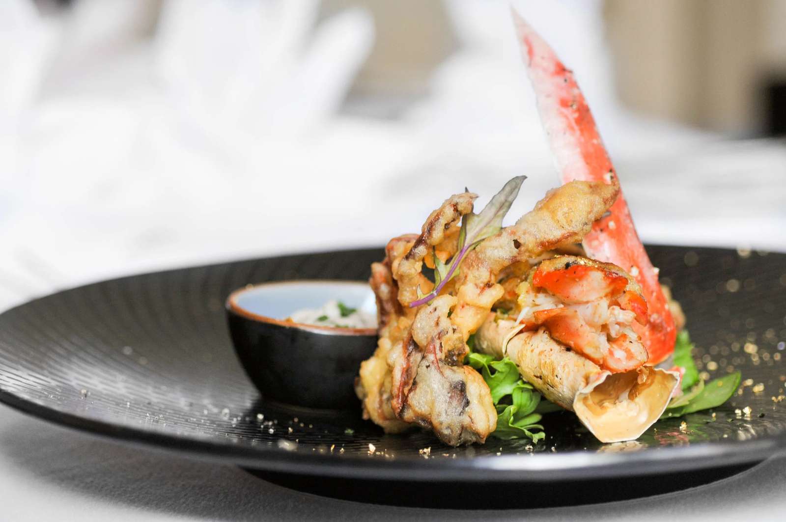 Plated king crab appetizer with dipping sauce at a fine dining restaurant