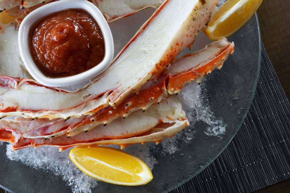 King crab claw served on ice with a bowl of dipping sauce