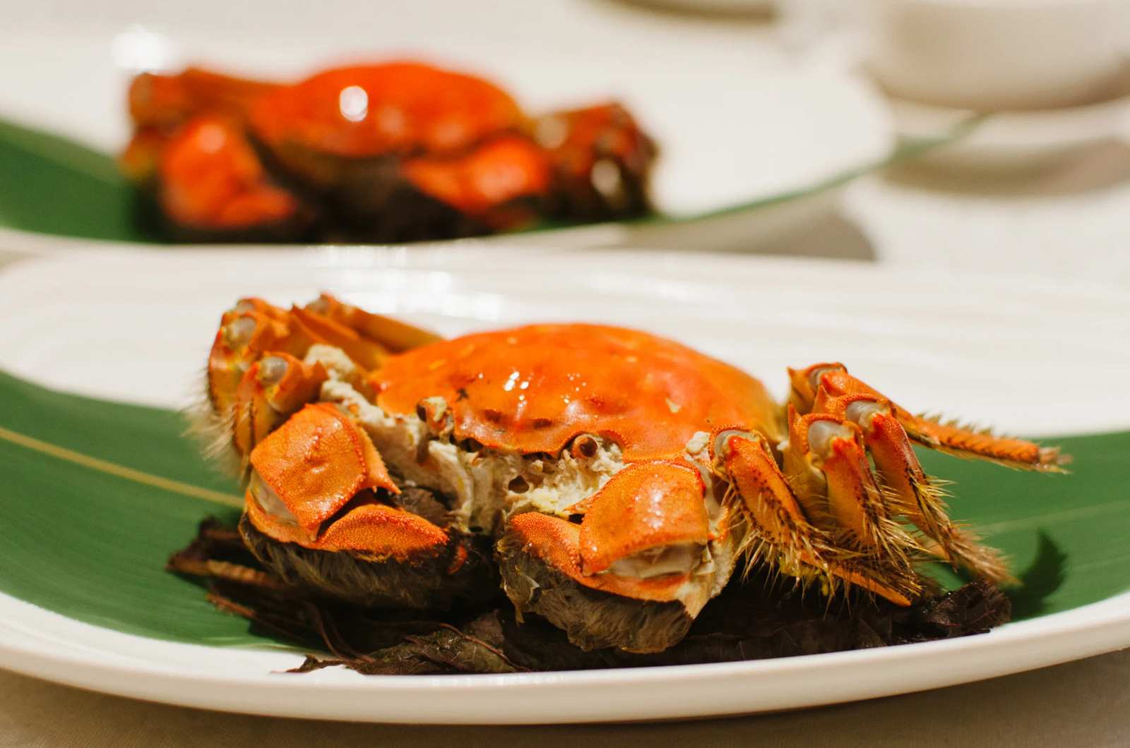 Whole cooked crab plated on a banana leaf garnish