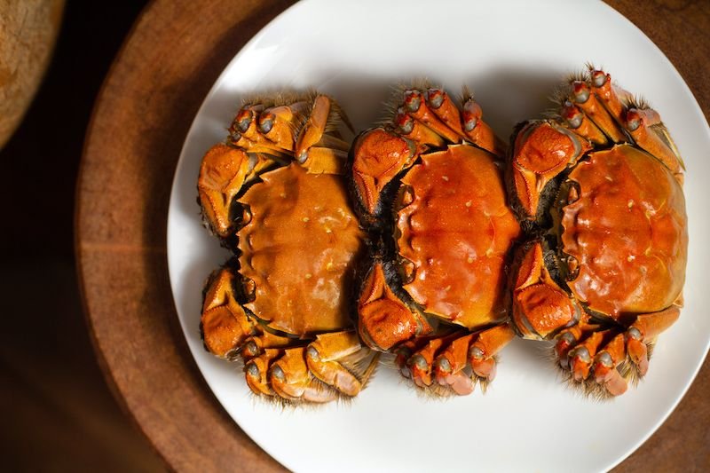 Three whole roasted mud crabs on a round white platter